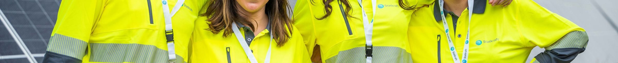 Team di donne e uomini che sorridono con pannelli fotovoltaici sullo sfondo